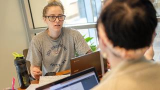 Two people talking at a desk.